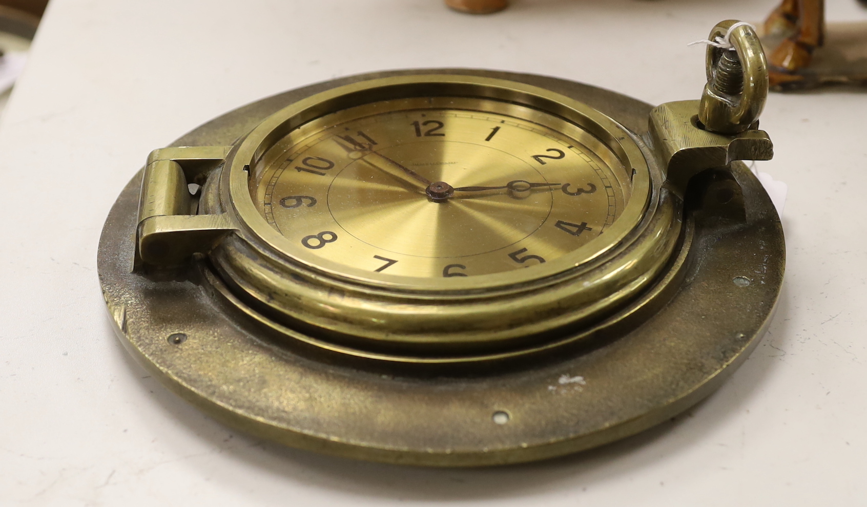 A brass porthole clock with Jaeger Le Coutre dial, total diameter 24cm